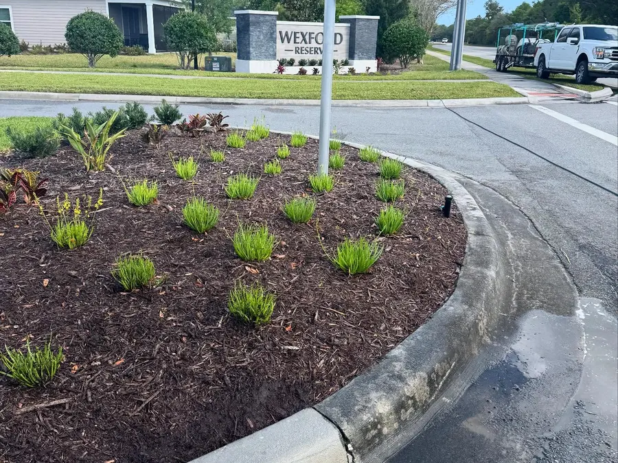 Curbs at a neighborhood entrance being pressure washed, cleaned and uncleaned sections side by side
