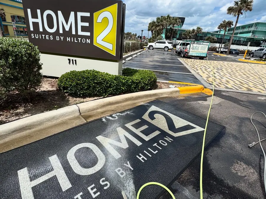 Hotel entrance pavers partway through pressure washing, with the cleaned section much lighter