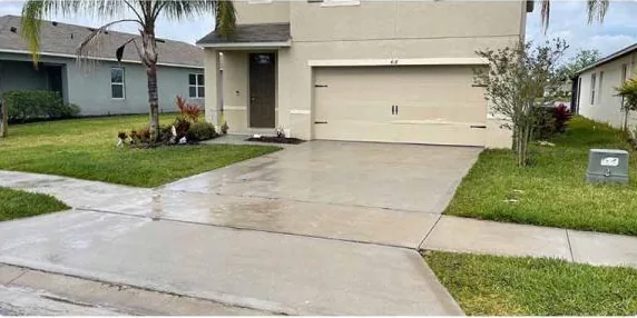 After: concrete driveway in front of a two-story home, cleaned