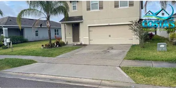 Before: concrete driveway in front of a two-story home