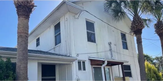 Before: two-story home with palm trees