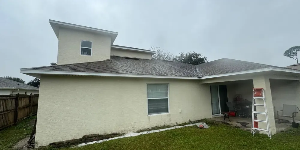 After: two-story stucco home with mildew along the walls, cleaned