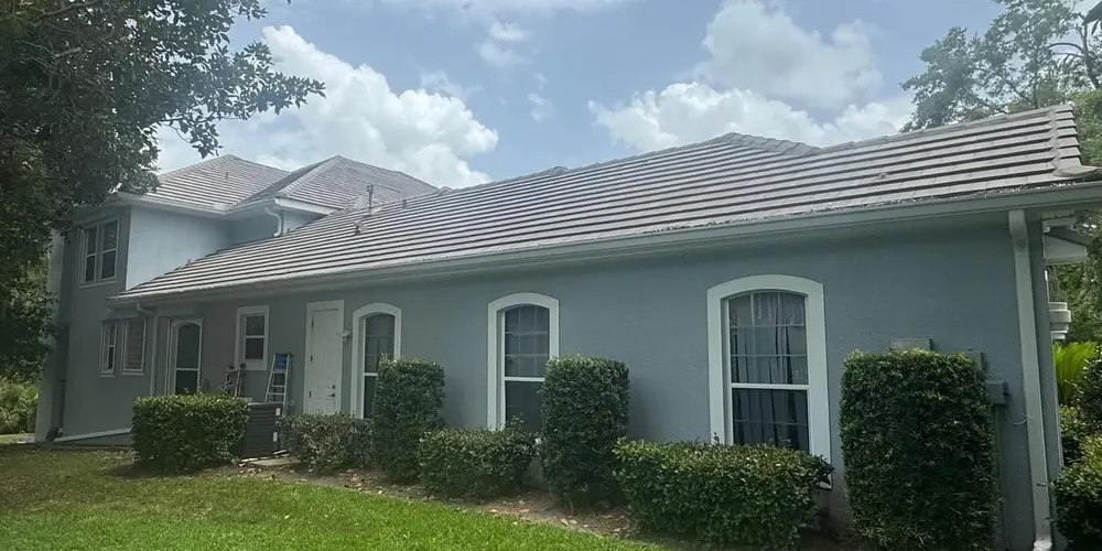 After: side of a stucco home with a tile roof, cleaned