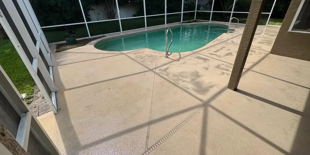 After: pool deck with dark mildew stains inside a screen enclosure, cleaned