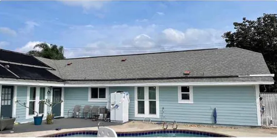 After: back of a home with a dark shingle roof, cleaned