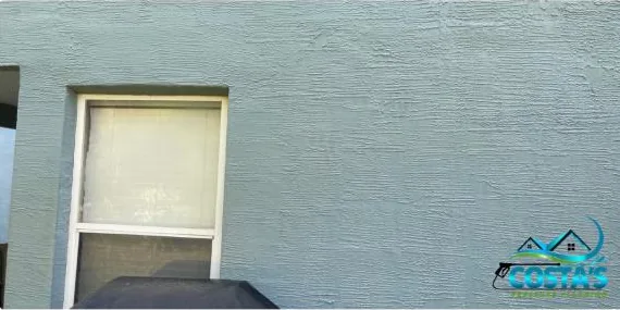 After: rust stains on a stucco wall between windows, cleaned