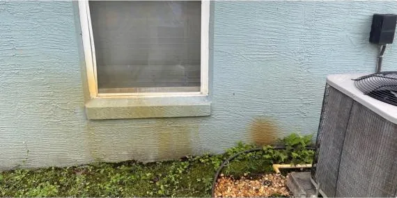 Before: rust stains under a window on a stucco wall