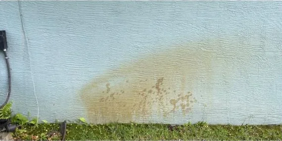 Before: orange rust stain on a stucco wall