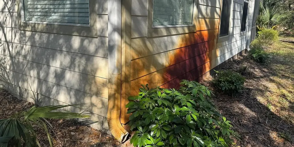 Before: corner of a home stained orange by sprinkler water