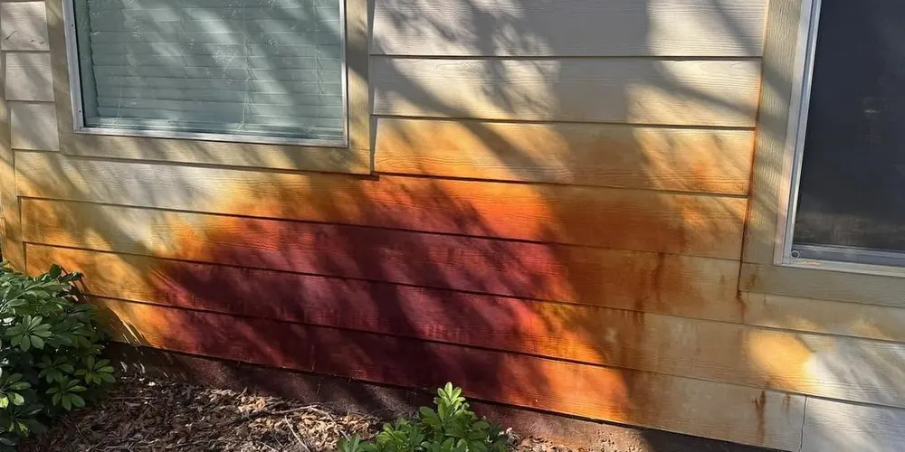 Before: siding with a heavy orange rust stain below a window