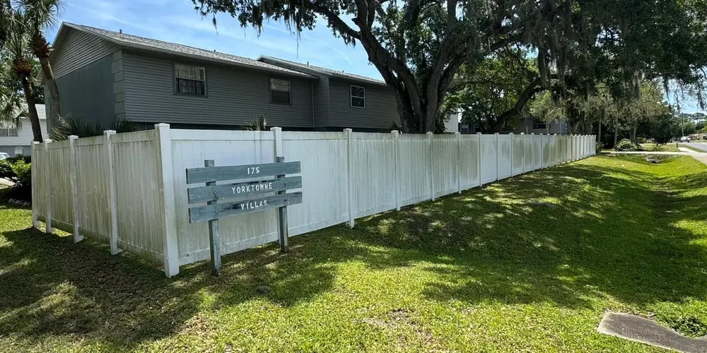 Before: white vinyl fence streaked with green mildew